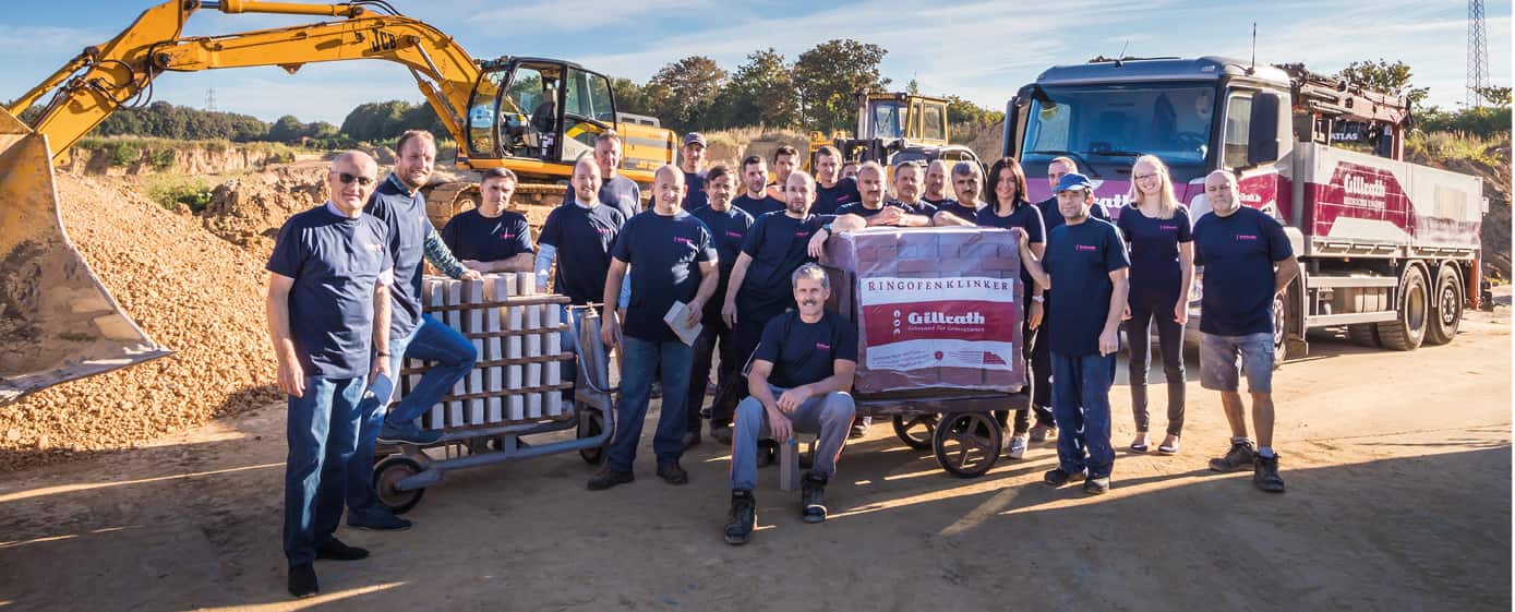 Das ganze Gillrath Team draußen - mit schwerem Gerät, aufgeschichteten Steinen und einer bereits verpackten Lieferung
